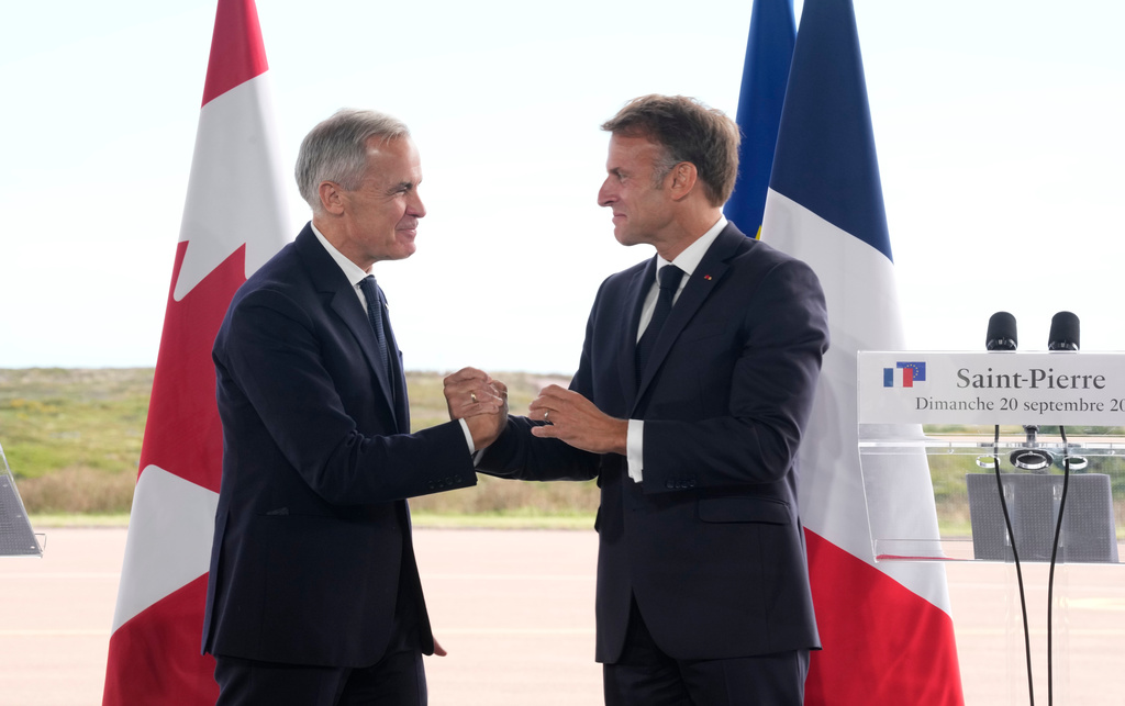 French President Emmanuel Macron, right, and Canadian Prime Minister Mark Carney embrace after delivering remarks in Saint-Pierre, Saint-Pierre-et-Miquelon, Sunday, Sept.20, 2026. (Adrian Wyld/The Canadian Press via AP)