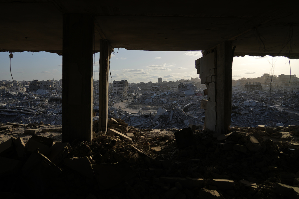 Displaced Palestinians walk amid destroyed buildings in the heavily damaged Sheikh Radwan neighborhood in Gaza City, Saturday, Oct. 11, 2025, after Israel and Hamas agreed to a pause in their war and the release of the remaining hostages. (AP Photo/Abdel Kareem Hana)