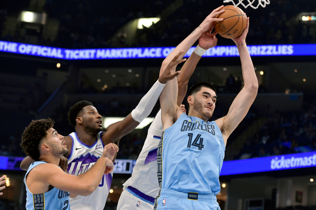 Memphis Grizzlies center Zach Edey (14) grabs a rebound ahead of, from left, guard Jahmai Mashack, Utah Jazz forward Jaren Jackson Jr., and center Jaxson Hayes in the first half of an NBA basketball game Wednesday, Oct. 21, 2026, in Memphis, Tenn. (AP Photo/Brandon Dill)