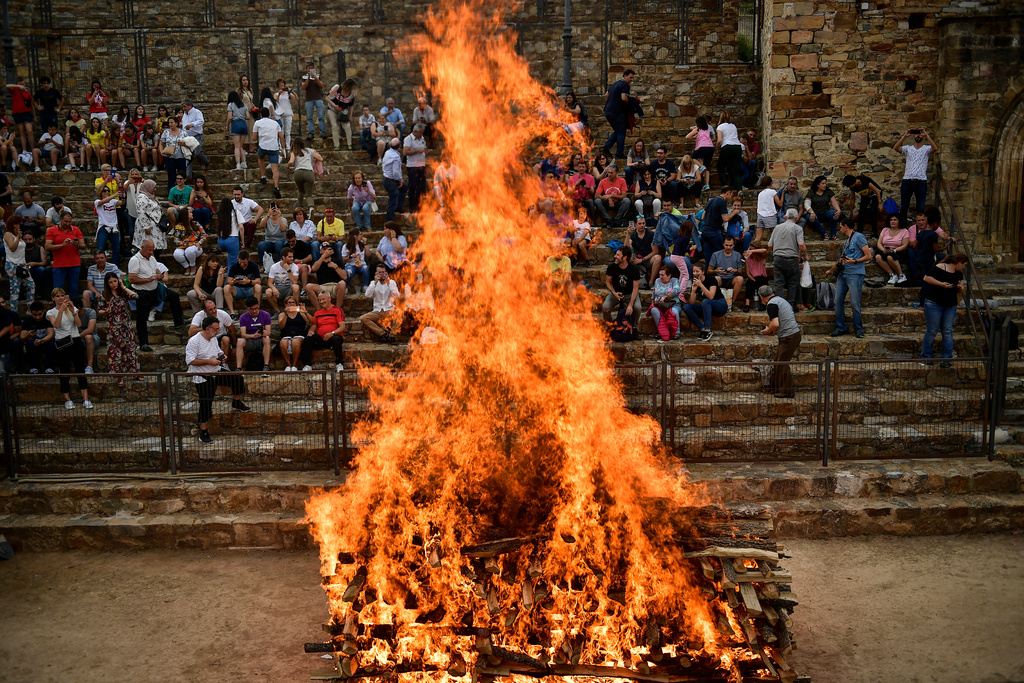 FILE - People view a fire before walking on the burning embers during the night of San Juan in San Pedro Manrique, northern Spain, June 23, 2019. (AP Photo/Alvaro Barrientos, File)