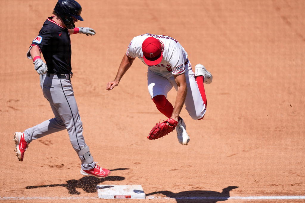 Los Angeles Angels second baseman Oswald Peraza, right, jumps as he misses a throw from first baseman Vaughn Grissom in an attempt to force Cleveland Guardians' Travis Bazzana out at first during the third inning of a baseball game Wednesday, Aug. 26, 2026, in Anaheim, Calif. (AP Photo/Mark J. Terrill)