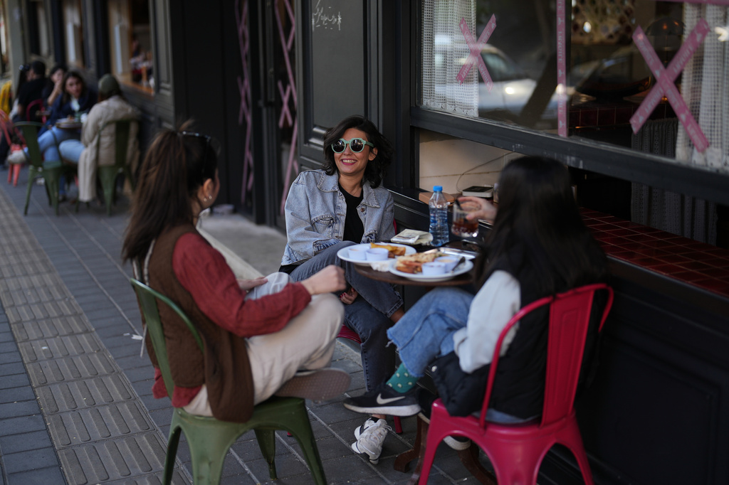Three young girls sit together over soft drinks and sandwiches at a café terrace in Tehran, Iran, Wednesday, April 8, 2026. (AP Photo/Francisco Seco)