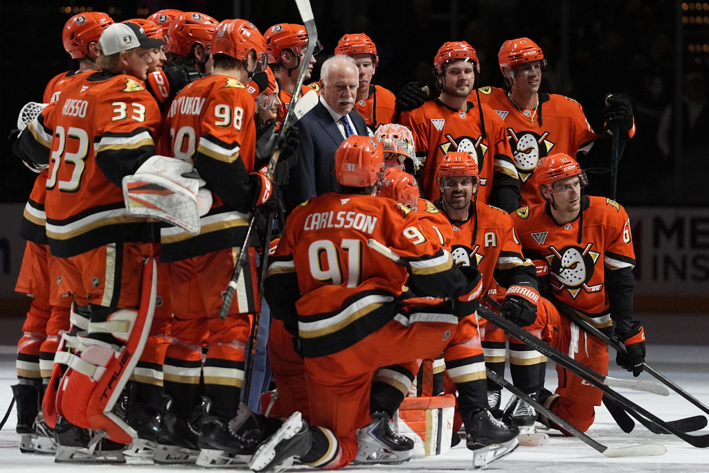 Anaheim Ducks head coach Joel Quenneville, center, poses with players and family after winning his 1,000th career coaching victory with a 6-4 win over the Edmonton Oilers in an NHL hockey game Wednesday, Feb. 25, 2026, in Anaheim, Calif. (AP Photo/Gregory Bull)