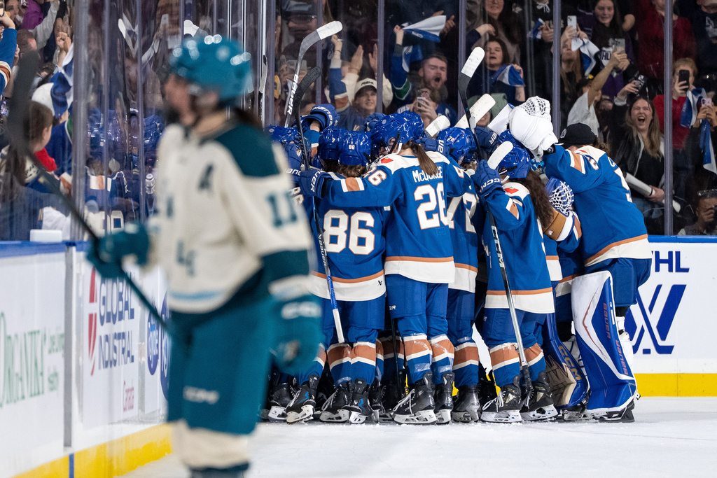 The Vancouver Goldeneyes celebrate defeating the Seattle Torrent as Emily Brown (11) skates to the bench during overtime PWHL hockey action in Vancouver, on Friday, Nov. 21, 2025. (Ethan Cairns/The Canadian Press via AP)