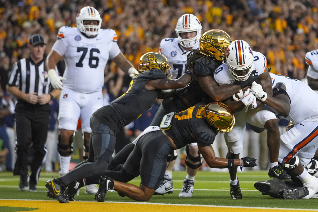 Auburn running back Damari Alston, right, pushes against Baylor defenders to score a touchdown run during the first half of an NCAA college football game Friday, Aug. 29, 2025, in Waco, Texas. (AP Photo/Julio Cortez)