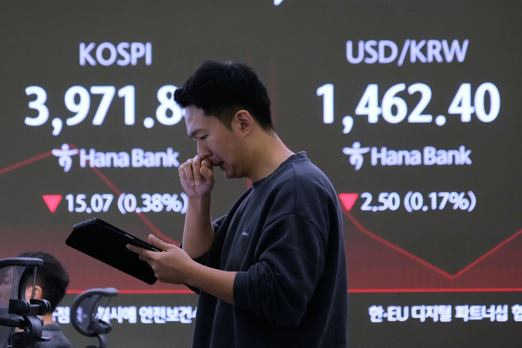 A currency trader works near a screen showing the Korea Composite Stock Price Index (KOSPI), left, and the foreign exchange rate between U.S. dollar and South Korean won at the foreign exchange dealing room of the Hana Bank headquarters in Seoul, South Korea, Friday, Nov. 28, 2025. (AP Photo/Ahn Young-joon)