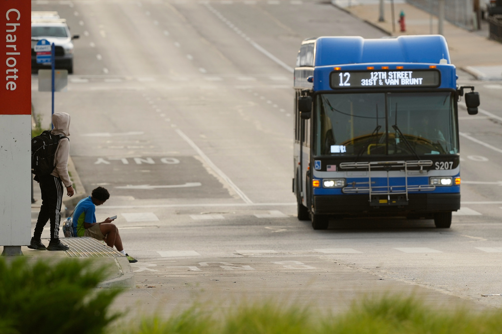 People wait for the bus at a transit center Friday, June 5, 2026, in Kansas City, Mo. (AP Photo/Charlie Riedel)