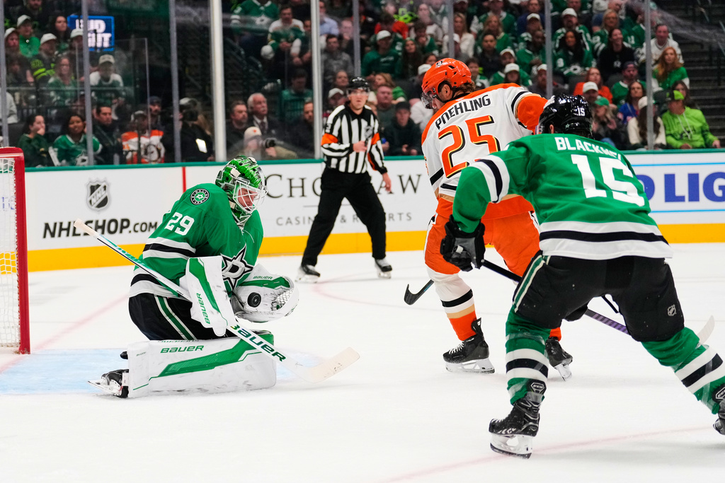 Dallas Stars goaltender Jake Oettinger (29) gloves a shot from Anaheim Ducks' Ryan Poehling (25) as Colin Blackwell (15) helps defend on the play in the second period of an NHL hockey game Thursday, Nov. 6, 2025, in Dallas. (AP Photo/Tony Gutierrez)