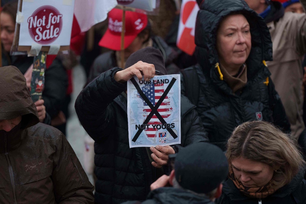 A man holds a map of Greenland covered in the American flag crossed out with an X during a protest against Trump's policy towards Greenland in front of the US consulate in Nuuk, Greenland, Saturday, Jan. 17, 2026. (AP Photo/Evgeniy Maloletka)