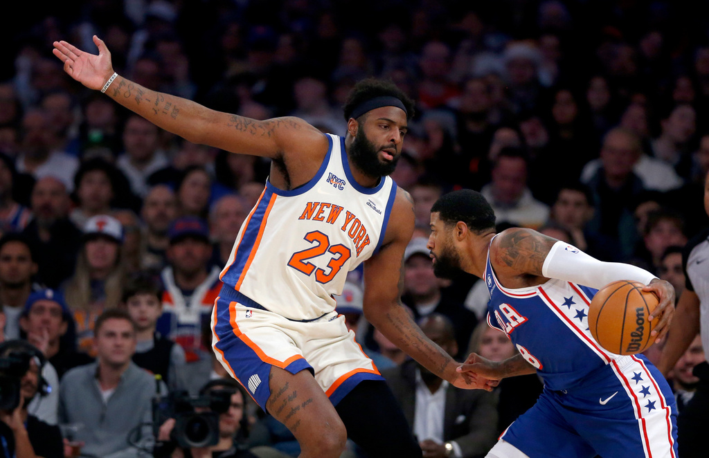 New York Knicks center Mitchell Robinson, left, defends Philadelphia 76ers forward Paul George, right, during the first half of an NBA basketball game, Saturday, Jan. 3, 2026, in New York. (AP Photo/John Munson)