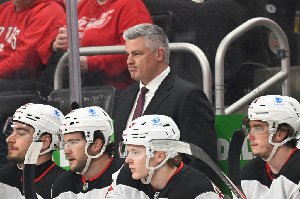 New Jersey Devils head coach Sheldon Keefe, center top, watches the first period of an NHL hockey game against the Detroit Red Wings, Saturday, April 11, 2026, in Detroit. (AP Photo/Jose Juarez)