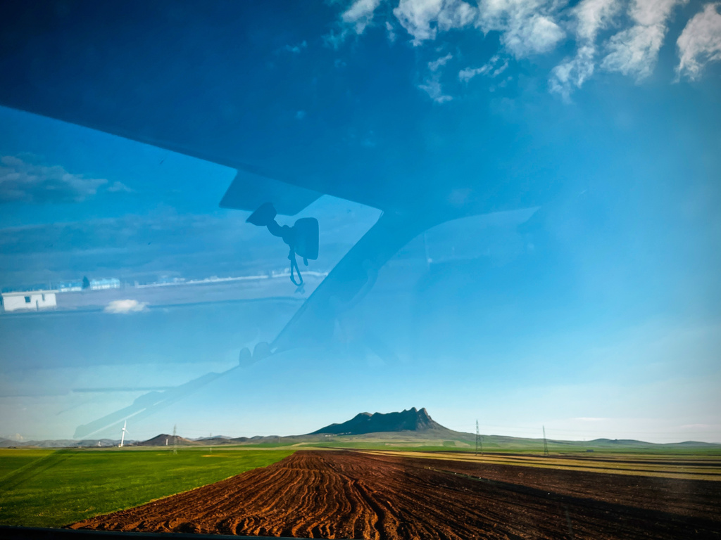 A cultivated field with a mountain range in the background, seen from a car on Road 2 between Takestan and Zanjan, Iran, Thursday, April 9, 2026. (AP Photo/Francisco Seco)