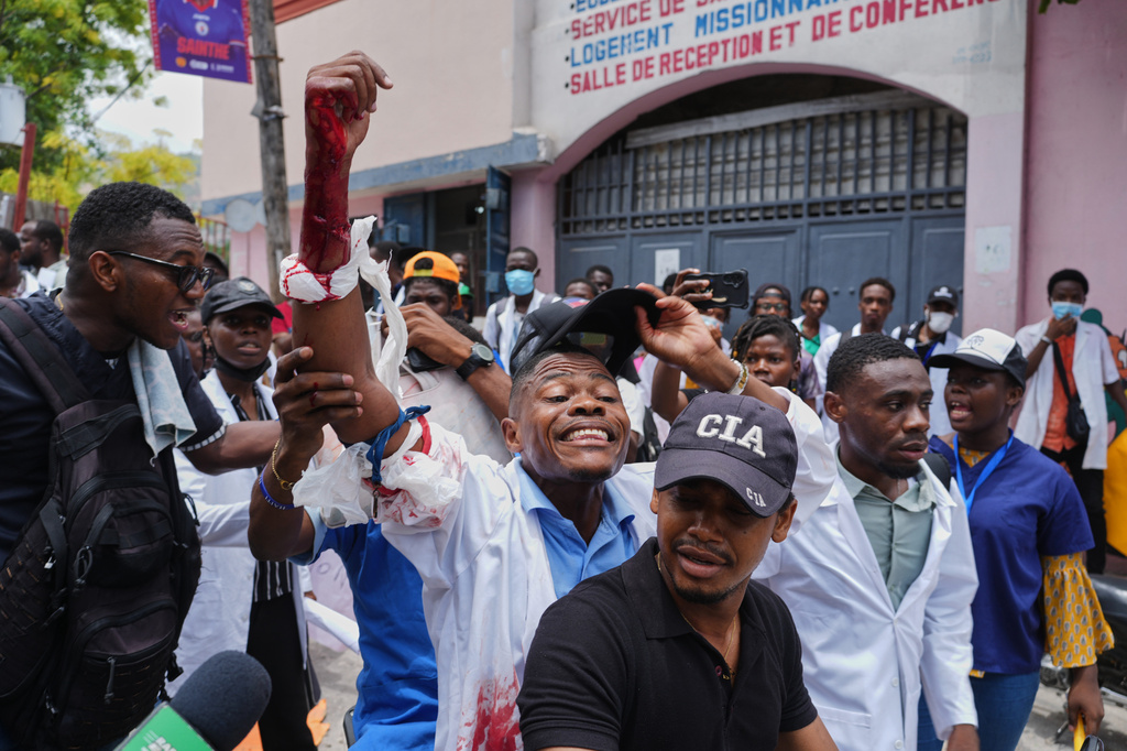Medical students help a fellow student shot by a uniformed policeman who fired trying to disperse the crowd during a protest march demanding the reopening of the General Hospital, in Port-au-Prince, Haiti, Wednesday, July 1, 2026. (AP Photo/Odelyn Joseph)