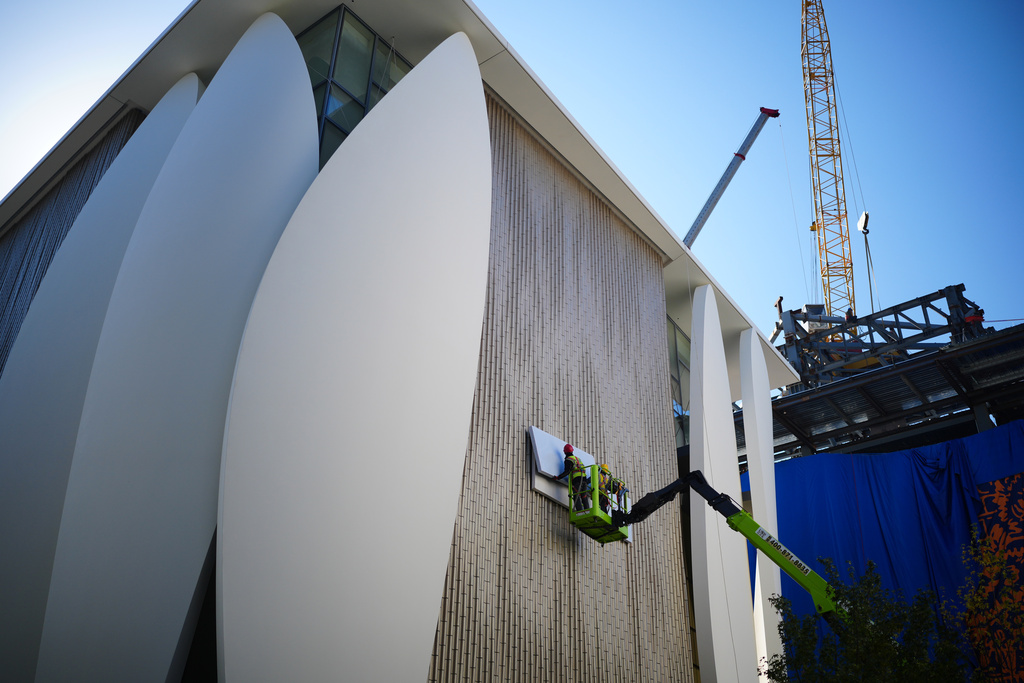 Workers on a platform install boards on a new fashion boutique under construction at the capital popular shopping district, in Beijing, Tuesday, Oct. 21, 2025. (AP Photo/Andy Wong)