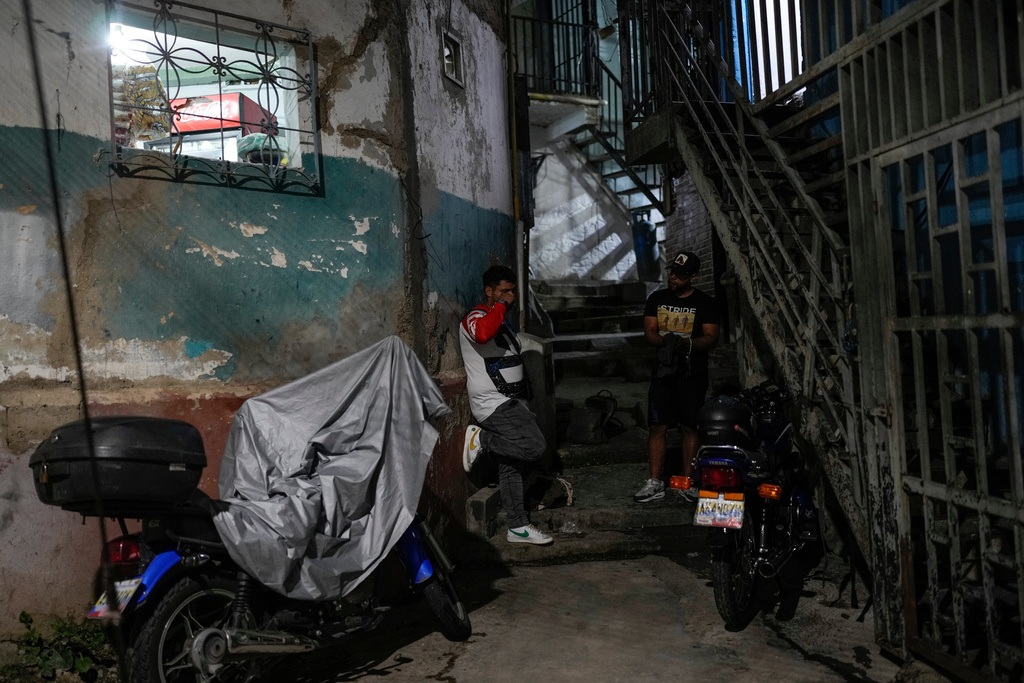 Enderson Betancur, left, talks with his cousin David Rodriguez outside their home in the Las Minas de Baruta neighborhood of Caracas, Venezuela, June 22, 2025. Both men traveled by land from Caracas to the U.S. border, crossing the Darien Gap, but were deported to Mexico by U.S. authorities and eventually gave up their hopes of reaching the United States, returning home. (AP Photo/Matias Delacroix)