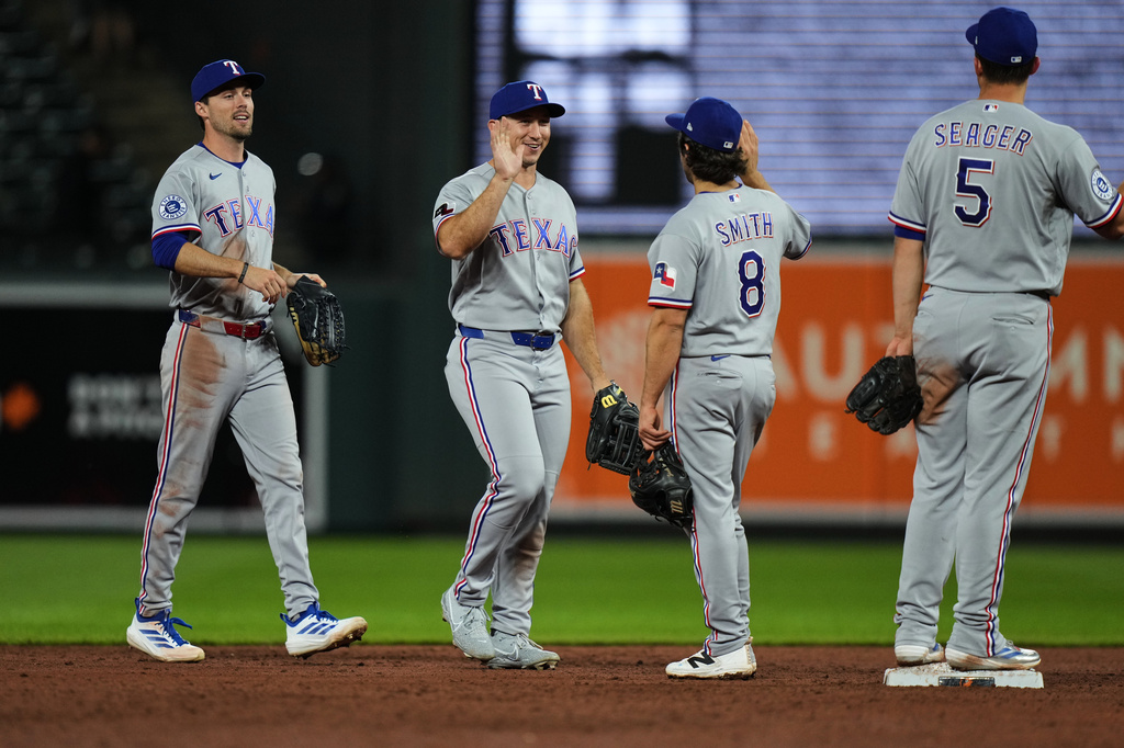 From left, Texas Rangers center fielder Evan Carter, left fielder Wyatt Langford, second baseman Josh Smith (8) and shortstop Corey Seager (5) celebrate their team's victory over the Baltimore Orioles in a baseball game, Monday, March 30, 2026, in Baltimore. (AP Photo/Stephanie Scarbrough)