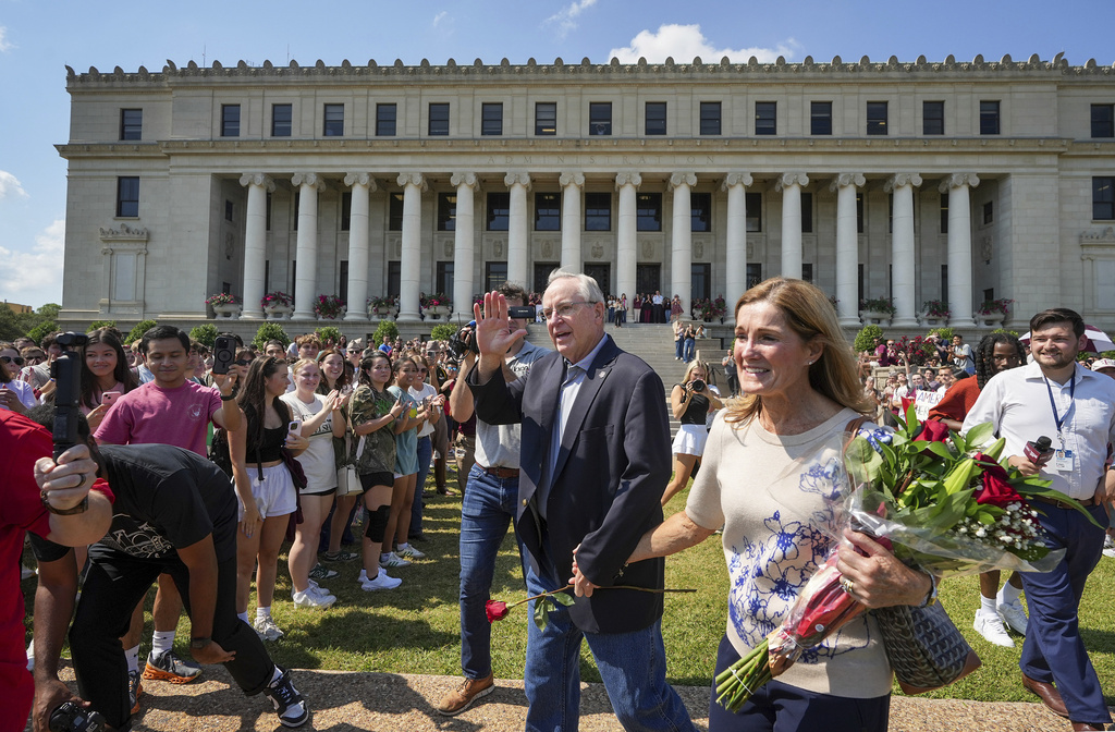 Texas A&M University President Mark Welsh, center, accompanied by his wife, Betty, exits the administration building after resigning in College Station, Texas, on Friday, Sept. 19, 2025. (Jay Janner/Austin American-Statesman via AP)