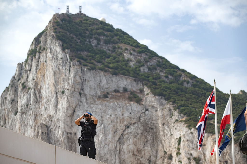 A Spanish police officer uses a pair of binoculars on the first day of passport-free travel under a new EU-U.K. treaty, at the border crossing between Gibraltar and Spain in La Línea de la Concepción, Spain, Wednesday, July 15, 2026. (AP Photo/Marcos Moreno)