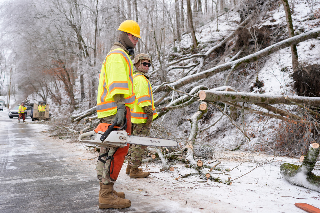 Tennessee National Guard Specialist Taylor Osteen, left, holds a chainsaw as he takes a break from cutting trees from a road Friday, Jan. 30, 2026, in Nashville, Tenn. (AP Photo/George Walker IV)