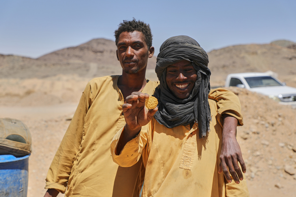 Miner Atta al-Khazin, right, shows a gold nugget produced by artisanal miners after processing ore at a mining site in Dalago Mahas, Sudan's Northern State, Friday, May 8, 2026.(AP Photo/Mohnd Blal)