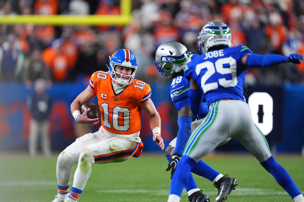 Denver Broncos quarterback Bo Nix, left, gets sacked by Seattle Seahawks linebacker Tyrice Knight, center, and cornerback Josh Jobe in overtime of an NFL football game Thursday, Oct. 15, 2026, in Denver. (AP Photo/David Zalubowski)