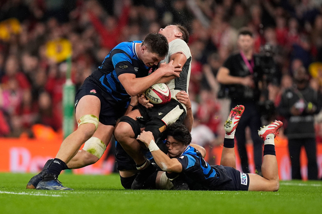 Japan's Harry Hockings, left, and Wales' Alex Mann, centre, battle for the ball during the rugby union Nations Series match between Wales and Japan at the Principality Stadium, Cardiff, Saturday, Nov. 15, 2025. (Andrew Matthews/PA via AP)