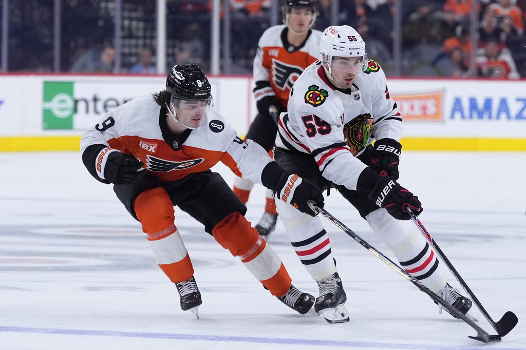 Philadelphia Flyers' Jamie Drysdale, left, knocks the puck away from Chicago Blackhawks' Artyom Levshunov during the third period of an NHL hockey game Thursday, March 26, 2026, in Philadelphia. (AP Photo/Matt Slocum)