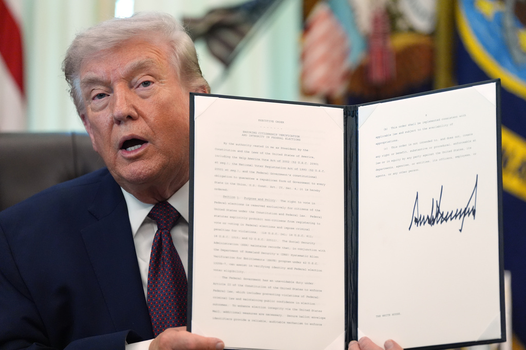 President Donald Trump holds a signed executive order in the Oval Office of the White House Tuesday, March 31, 2026, in Washington. (AP Photo/Alex Brandon)