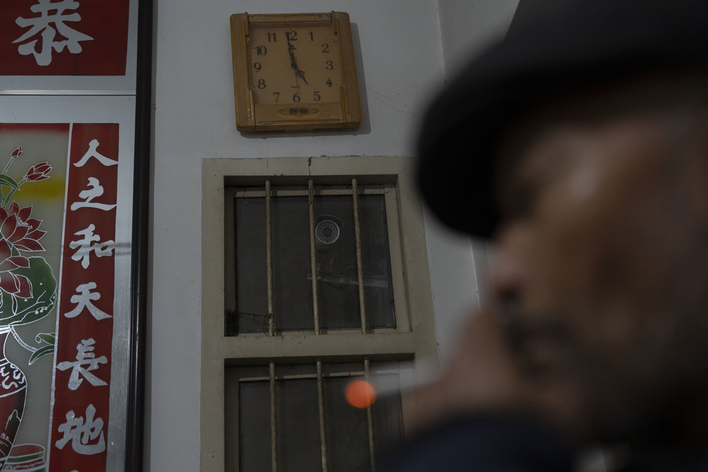 Petitioner Yang Guoliang smokes near a security camera his family installed inside their home in Changzhou in eastern China's Jiangsu Province, Friday, Dec. 13, 2024. (AP Photo/Ng Han Guan)