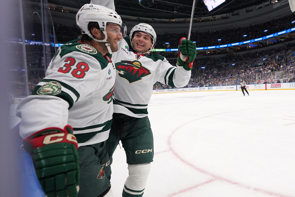 Minnesota Wild's Ryan Hartman (38) is congratulated by teammate Brock Faber after scoring during the first period of an NHL hockey game against the St. Louis Blues Thursday, Oct. 9, 2025, in St. Louis. (AP Photo/Jeff Roberson)