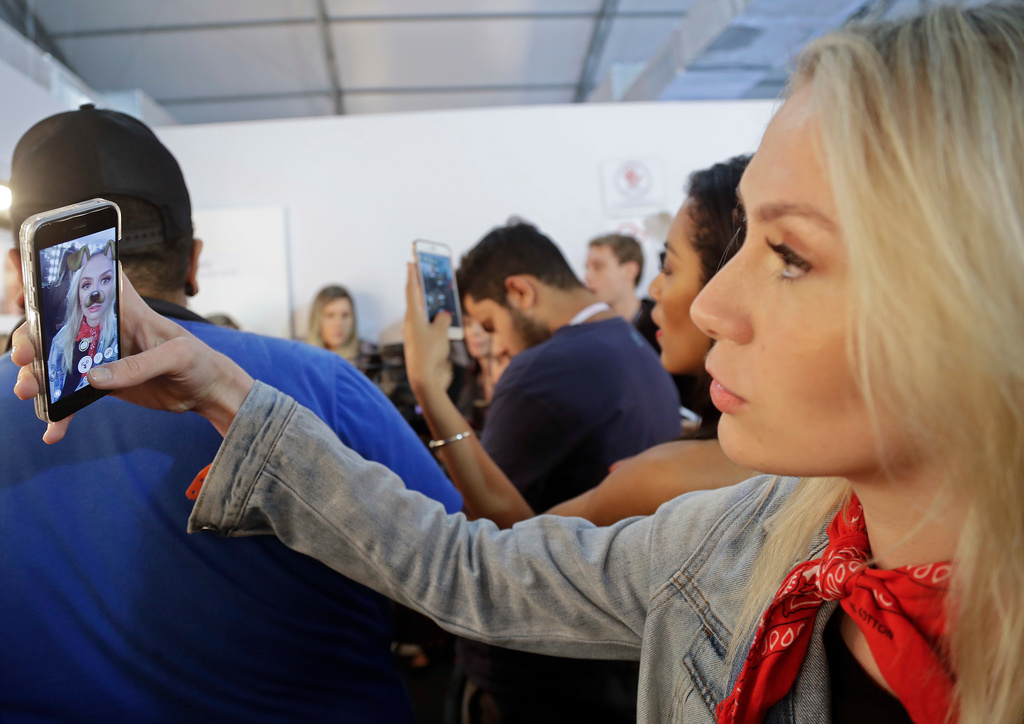 FILE - A model uses Snapchat as she prepares backstage for the Samuel Cirnansck collection during Sao Paulo Fashion Week in Sao Paulo, Brazil, Thursday, Oct. 27, 2016. (AP Photo/Andre Penner, File)