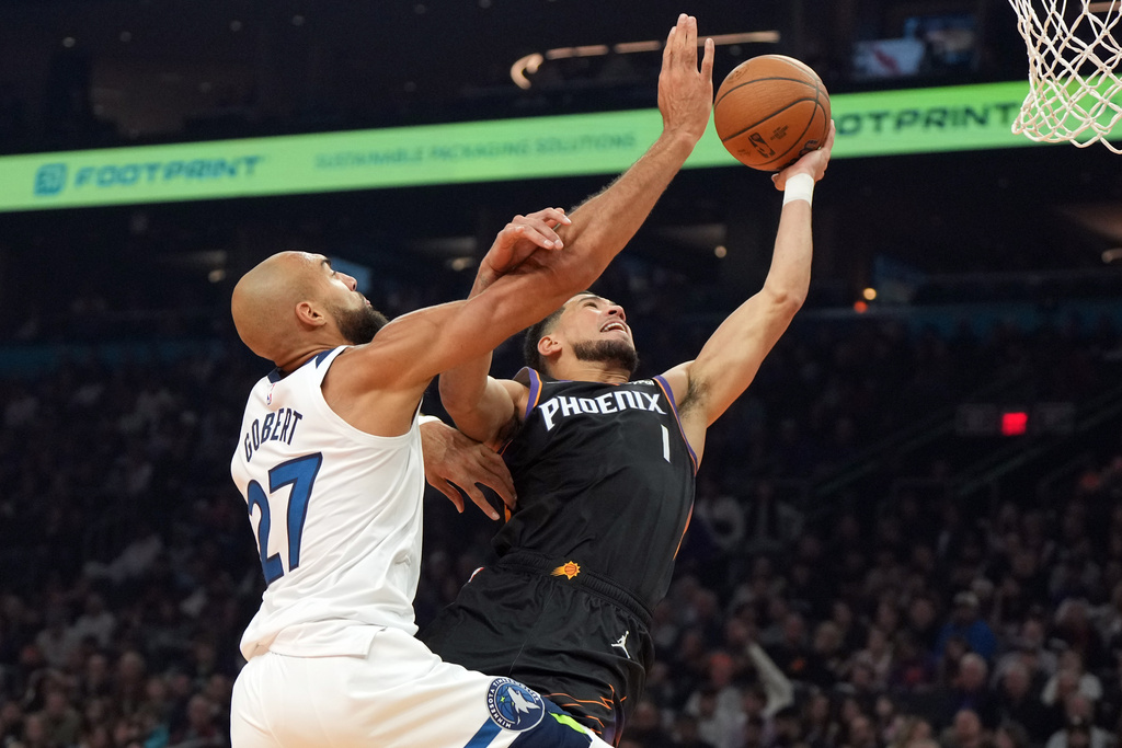 Phoenix Suns guard Devin Booker, right, drives past Minnesota Timberwolves center Rudy Gobert (27) during the first half of an NBA Cup basketball game, Friday, Nov. 21, 2025, in Phoenix. (AP Photo/Rick Scuteri)
