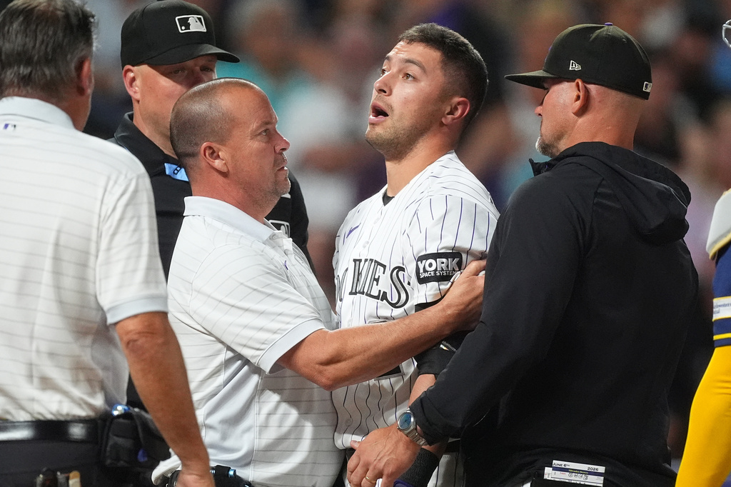 Colorado Rockies' Tyler Freeman, center, is tended to by trainer Heath Townsend, center left, as manager Warren Schaeffer, right, looks on after he was hit on the helmet by a pitch from Milwaukee Brewers starter Jacob Misiorowski in the sixth inning of a baseball game Saturday, June 6, 2026, in Denver. (AP Photo/David Zalubowski)