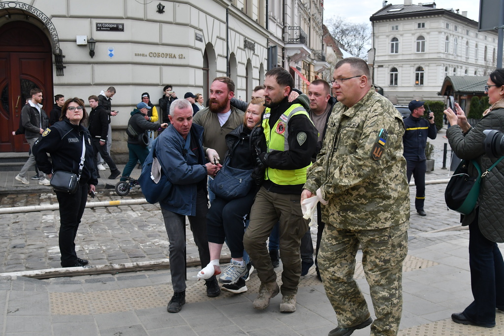 Volunteers help an injured woman following Russia's drone attack in the city center in Lviv, Ukraine, Tuesday, March 24, 2026. (AP Photo/Mykola Tys)