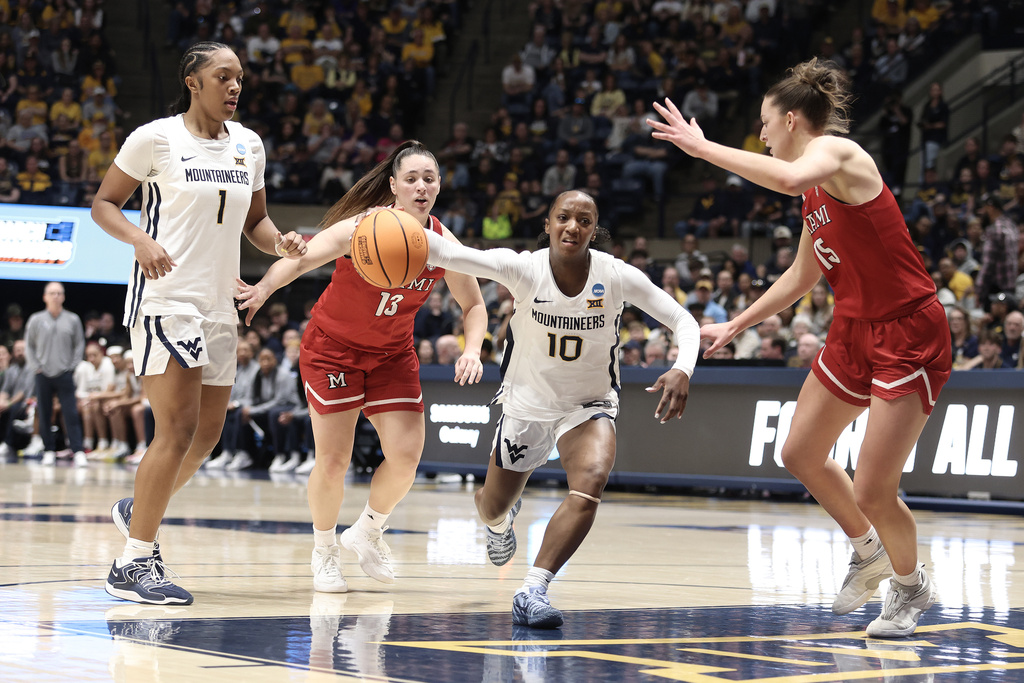 West Virginia guard Jordan Harrison (10) drives Miami (Ohio) guard Tamar Singer (13) and forward Amber Tretter (15) defend as West Virginia forward Carter McCray (1) watches in the first half in the first round of the NCAA college basketball tournament, Saturday, March 21, 2026, in Morgantown, W.Va. (AP Photo/Kathleen Batten)
