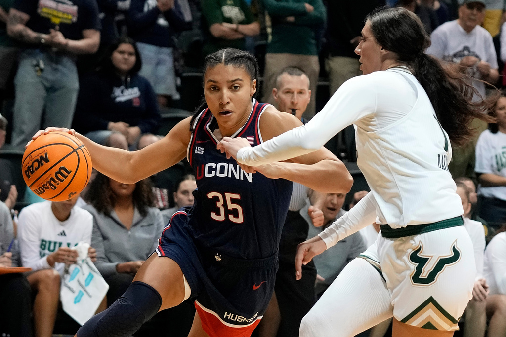 UConn guard Azzi Fudd (35) drives aropund South Florida guard Katie Davidson during the first quarter of an NCAA college basketball game Tuesday, Dec. 2, 2025, in Tampa, Fla. (AP Photo/Chris O'Meara)