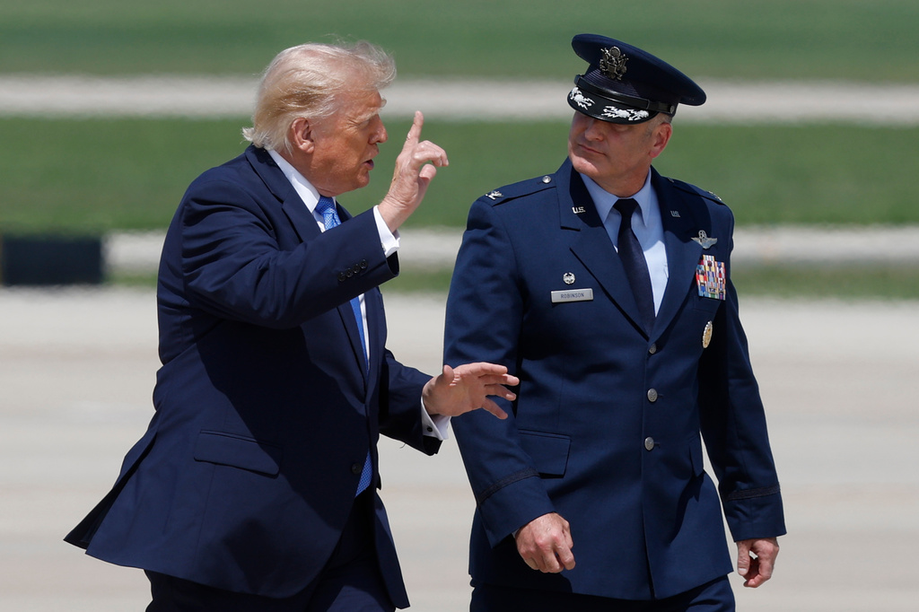President Donald Trump, left, is escorted by Air Force Col. Christopher M. Robinson, commander of the 89th Airlift Wing, right, as he walk from Marine One to Air Force One, at Joint Base Andrews, Md., Tuesday, Aug. 4, 2026. (AP Photo/Luis M. Alvarez)