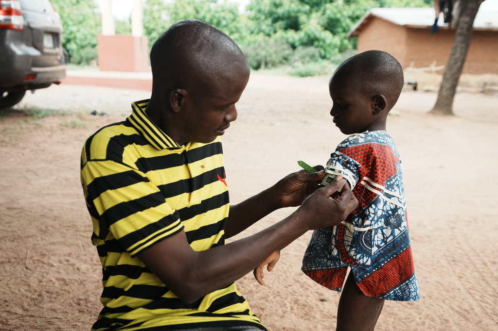Douro Wonkourou Idrissou, who described himself as a nutrition support member, uses a tape to measure the circumference of a child's upper arm, in N'dali, northern Benin, Sunday, May. 17, 2026. (AP Photo/Sunday Alamba)