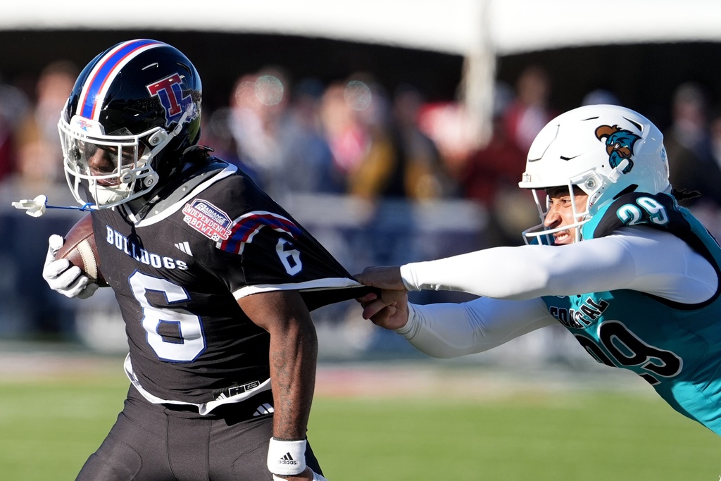 Louisiana Tech wide receiver Tre Averhart (6) is grabbed by a Coastal Carolina defensive player during the second half of the Independence Bowl NCAA college football game, Tuesday, Dec. 30, 2025, in Shreveport, La. (AP Photo/Rogelio V. Solis)