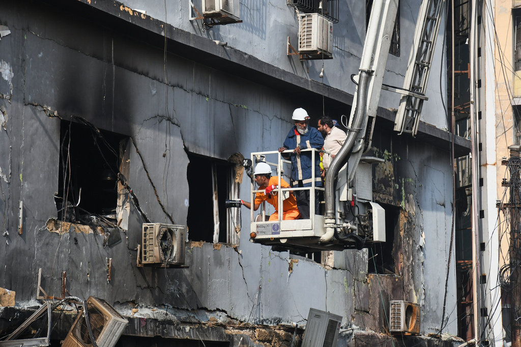 Firefighters search through the rubble of a burnt building of a multistory shopping plaza following a massive fire in Karachi, Pakistan, Monday, Jan. 19, 2026. (AP Photo/Ali Raza)