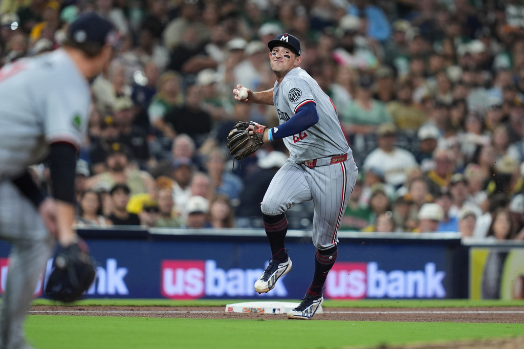 Minnesota Twins third baseman Brooks Lee throws to first too late as San Diego Padres' Austin Hays arrives safely with a single during the fifth inning of a baseball game Friday, Aug. 21, 2026, in San Diego. (AP Photo/Gregory Bull)