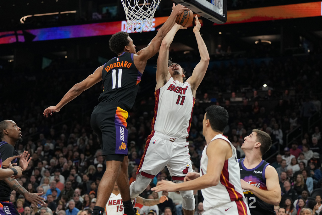 Phoenix Suns forward Oso Ighodaro, center left, blocks a shot by Miami Heat forward Jaime Jaquez Jr., center right, during the first half of an NBA basketball game, Sunday, Jan. 25, 2026, in Phoenix. (AP Photo/Rick Scuteri)