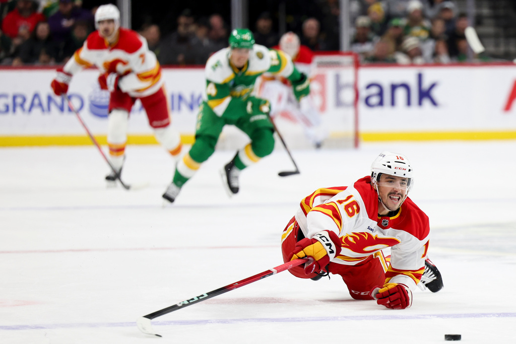 Calgary Flames center Morgan Frost (16) dives for the puck during the second period of an NHL hockey game against the Minnesota Wild, Sunday, Nov. 9, 2025, in St. Paul, Minn. (AP Photo/Ellen Schmidt)