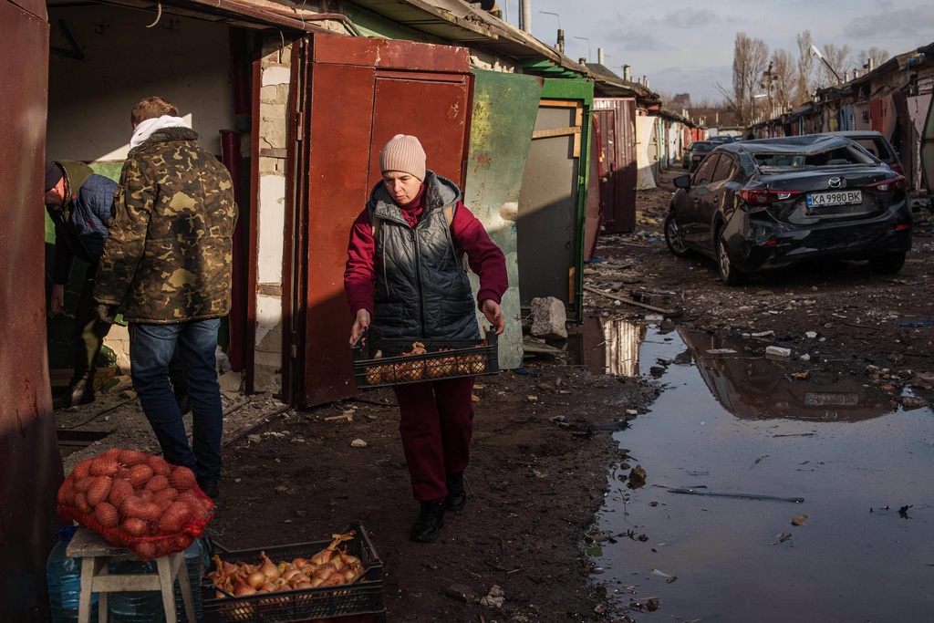 A woman collects salvaged food from her garage damaged after a Russian strike on Kyiv, Ukraine, on Tuesday, Nov. 25, 2025. (AP Photo/Evgeniy Maloletka)