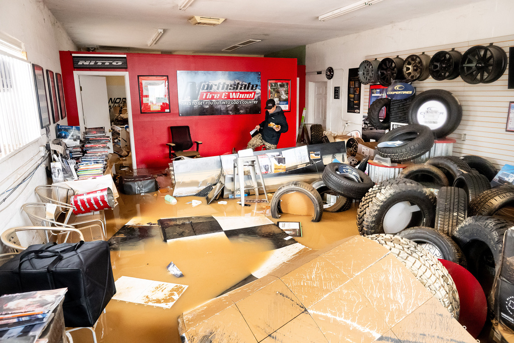 Dekoda Cruz walks through the flooded office of Northstate Tire & Wheel following heavy rains on Monday, Dec. 22, 2025, in Redding, Calif. (AP Photo/Noah Berger)