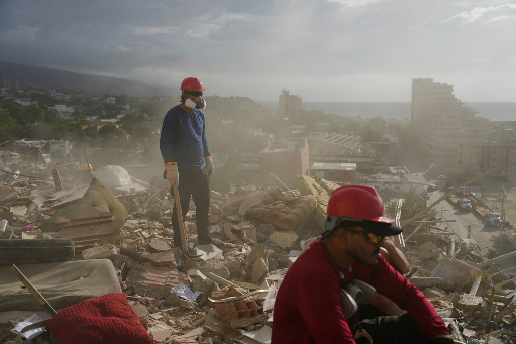FILE - Rescue workers and volunteers search through the rubble of a building collapsed during the earthquakes in La Guaira, Venezuela, July 6, 2026. (AP Photo/Ariana Cubillos, File)