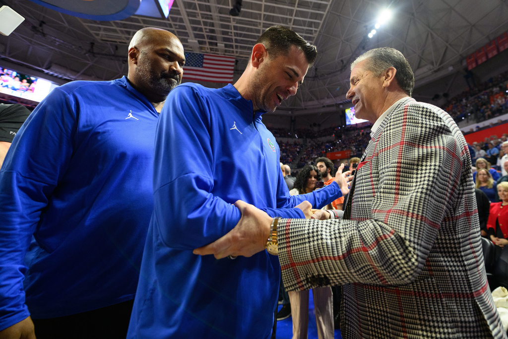 Florida head coach Todd Golden, center, shakes hands with Arkansas head coach John Calipari, right, before an NCAA college basketball game, Saturday, Feb. 28, 2026, in Gainesville, Fla. (AP Photo/Noah Lantor)