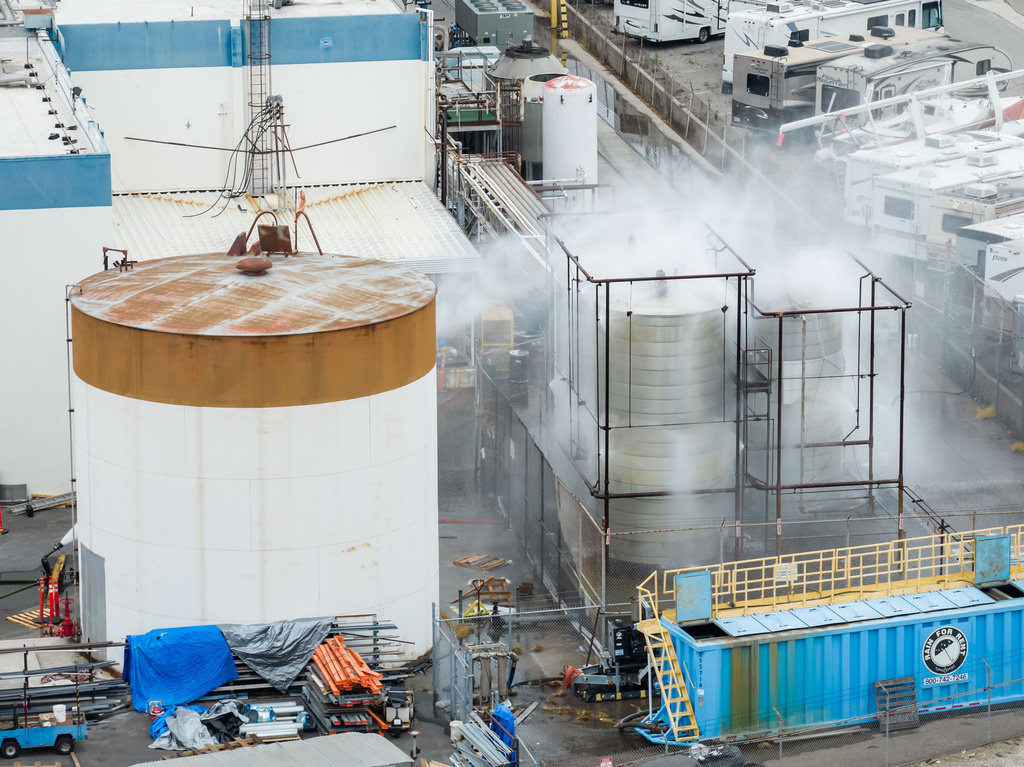 Water is sprayed on a damaged tank at GKN Aerospace in Garden Grove, Calif., on Sunday, May 24, 2026, after the tank containing a chemical used to make plastic parts overheated Thursday. (AP Photo/Ethan Swope)