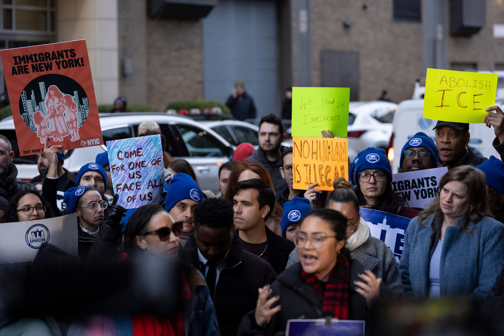 People raise signs during a news conference outside Greater New York Federal Building, Tuesday, Jan. 13, 2026, in New York. (AP Photo/Yuki Iwamura)