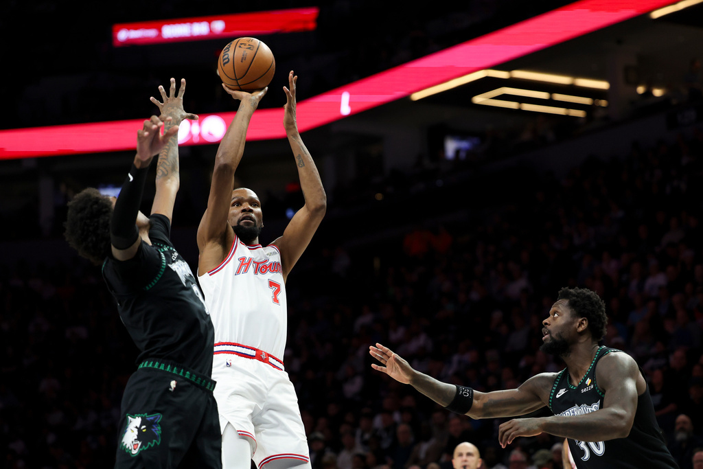 Houston Rockets forward Kevin Durant (7) shoots against Minnesota Timberwolves forward Jaden McDaniels, left, and forward Julius Randle (30) during the first half of an NBA basketball game, Wednesday, March 25, 2026, in Minneapolis. (AP Photo/Ellen Schmidt)